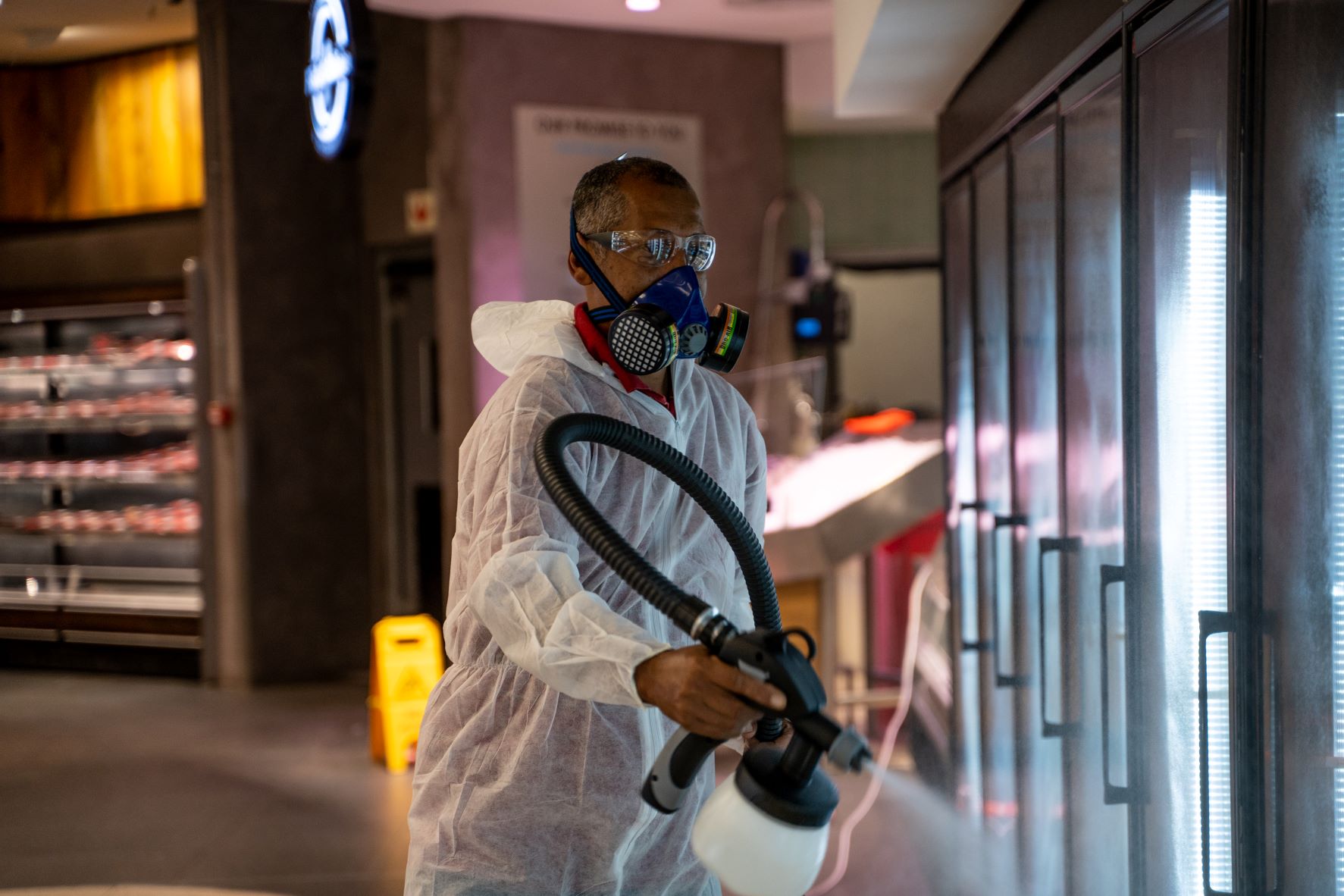 Cleaning operative in personal protective equipment is using a fogger to disinfect surfaces